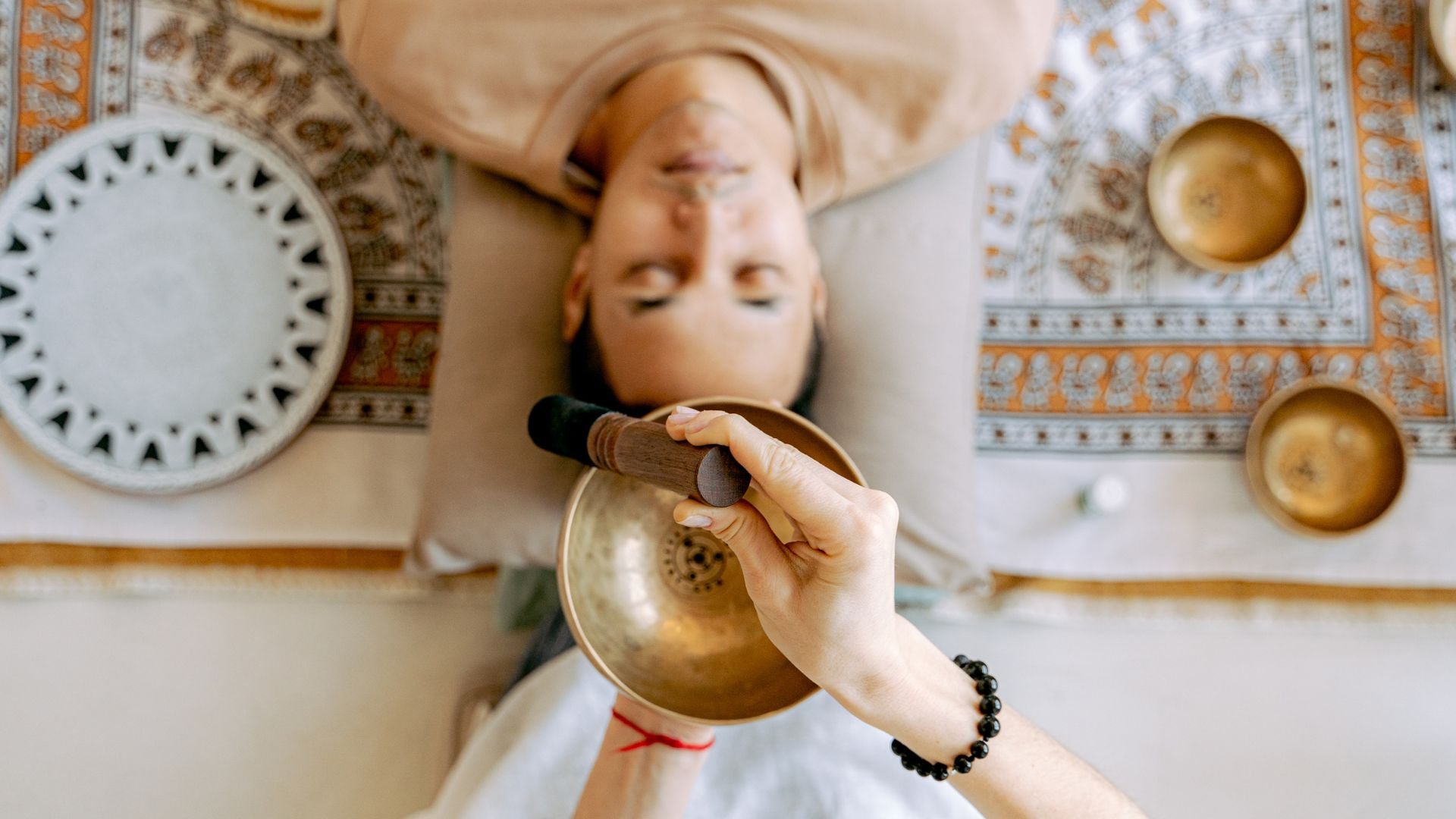 Person receiving sound healing with Tibetan singing bowl during relaxation